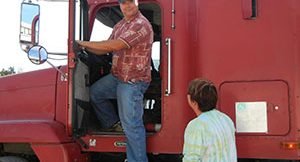 image of man on ledge of truck, a second man looks up at him