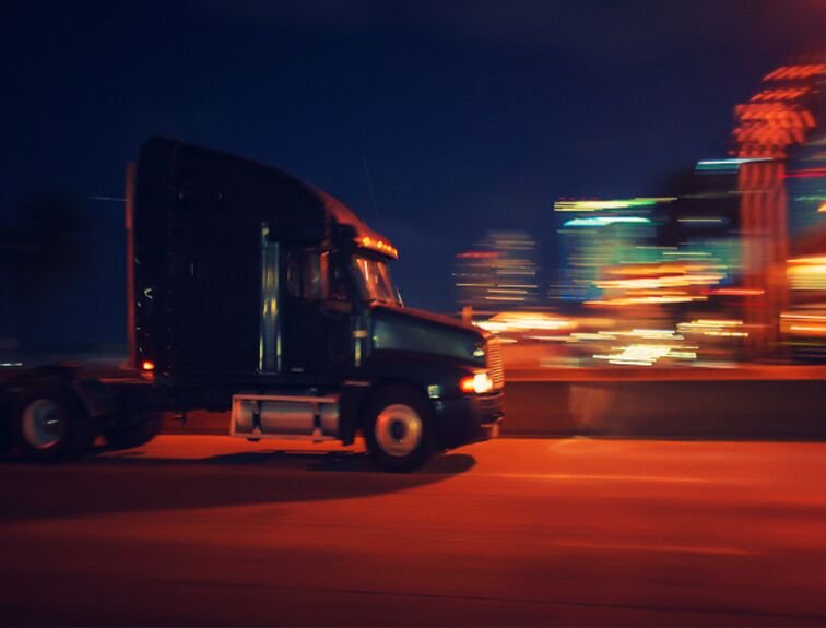 image of semi truck driving in the city at night, blurred to show motion