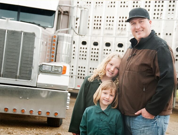 image of dad with 2 daughters smiling standing in front of white semi truck