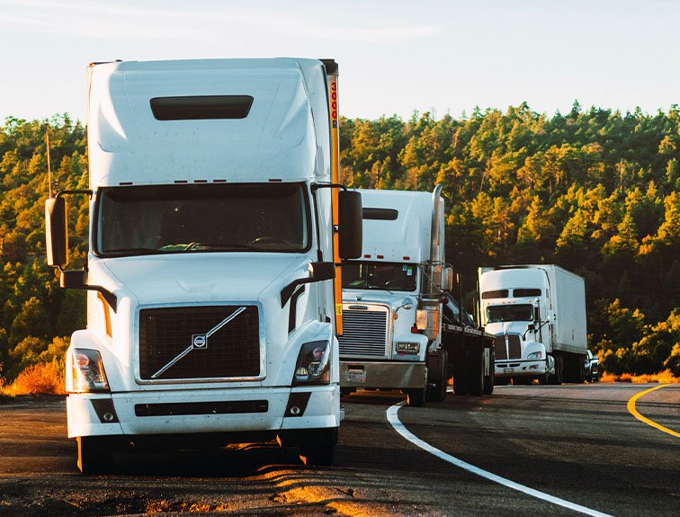 image of 3 white semi trucks parked on side of road