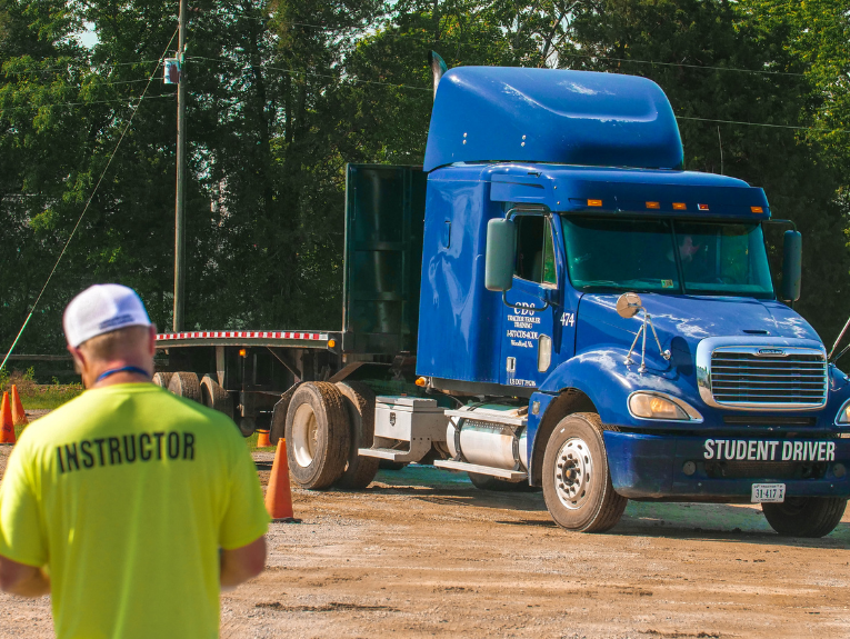 image of CDL truck driver instructor with blue flat bed truck in background