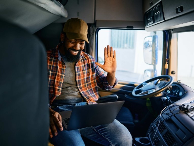 image of a truck driver in his truck doing a video call on his laptop